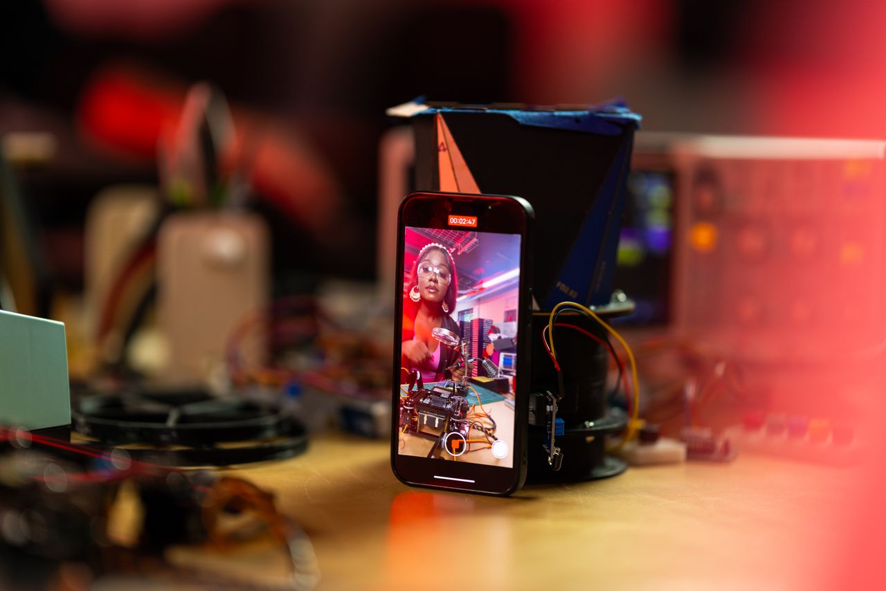 Crafting Captivating Headlines: Your awesome post title goes here Black woman live streaming tech video on smartphone in an electronics workshop.